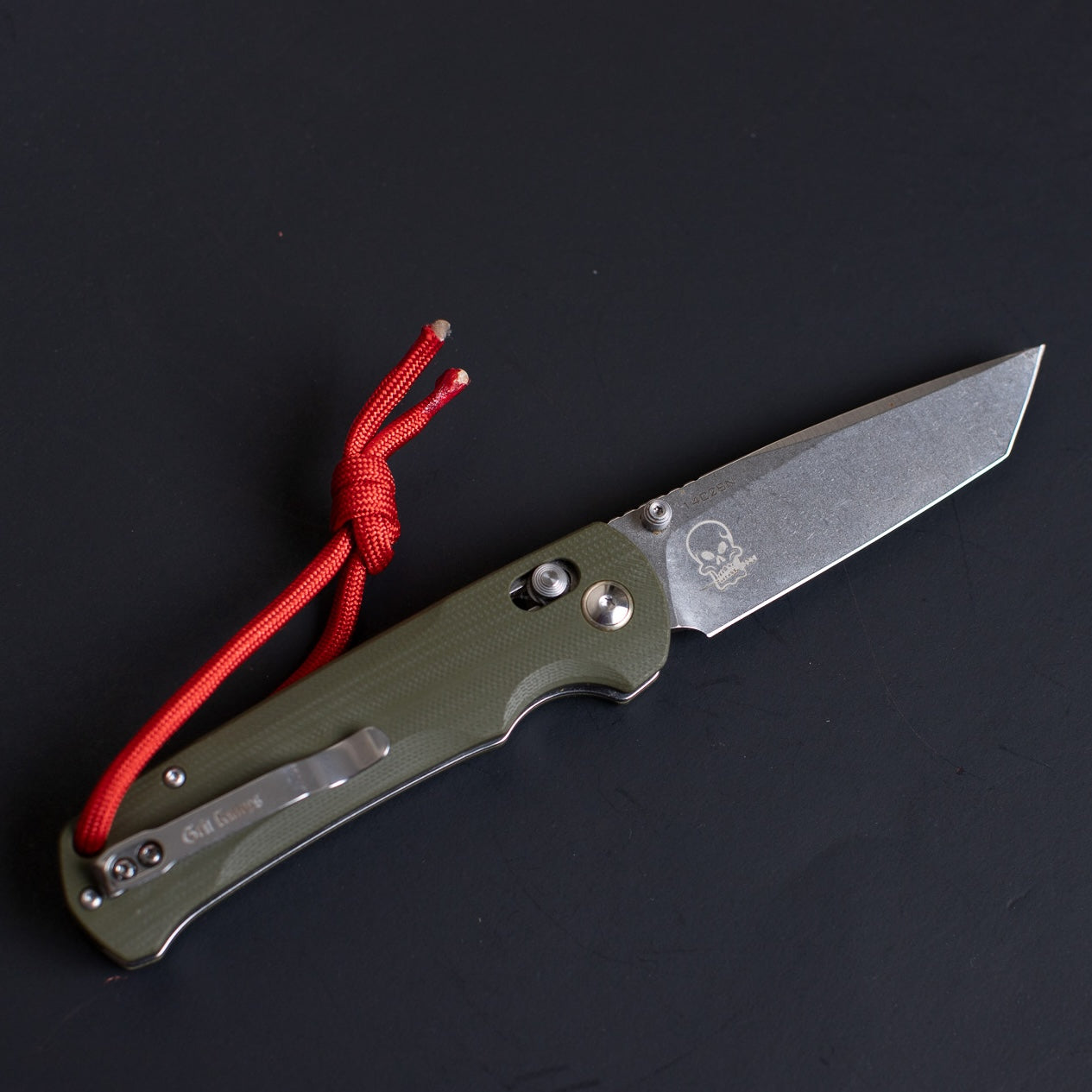 Folding knife with a red cord on a black background