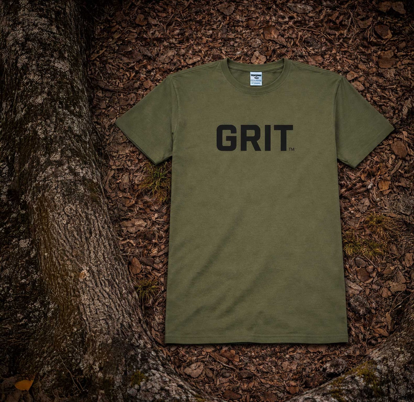 Green t-shirt with 'GRIT' text on a forest floor background
