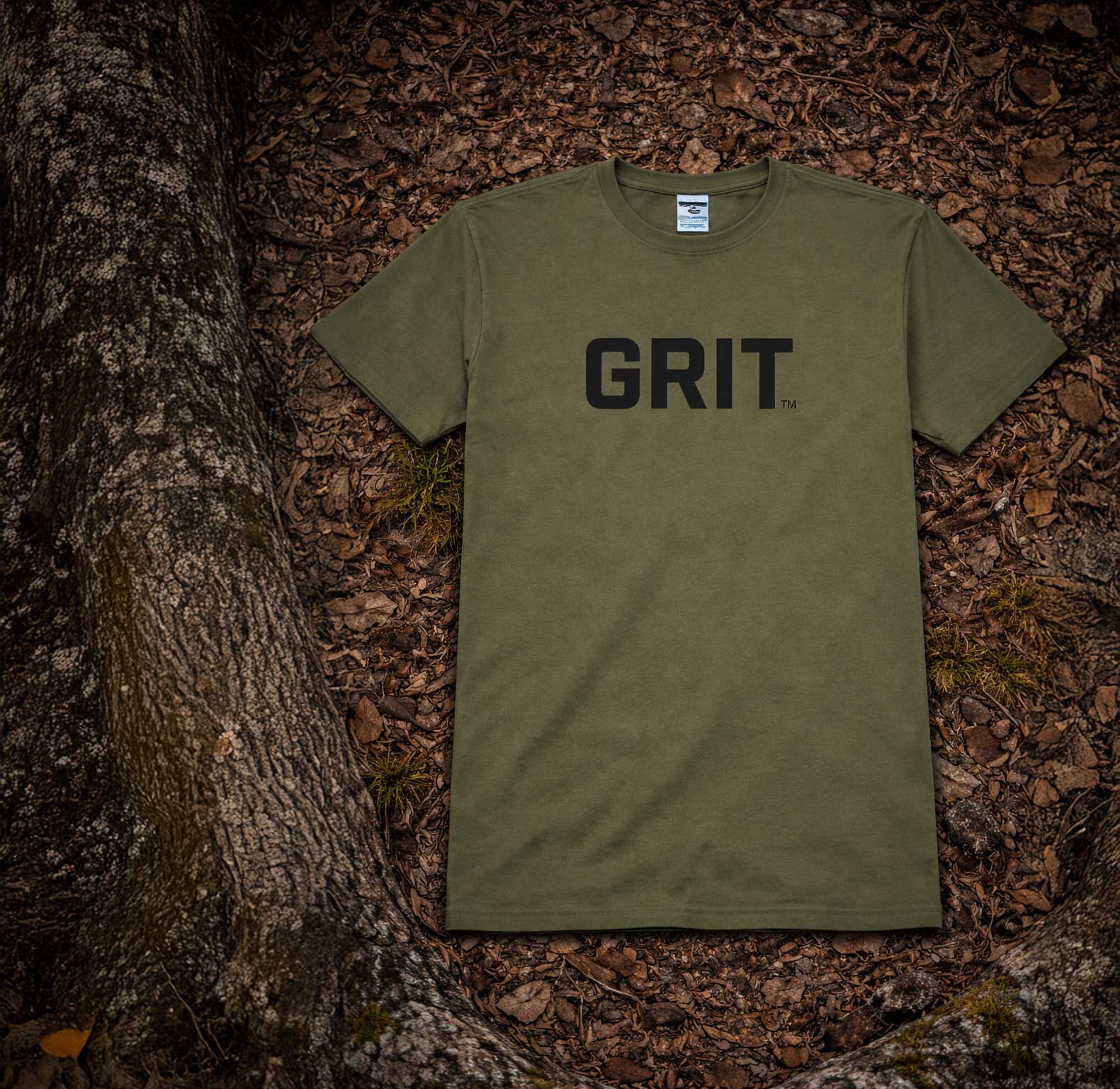 Green t-shirt with 'GRIT' text on a forest floor background