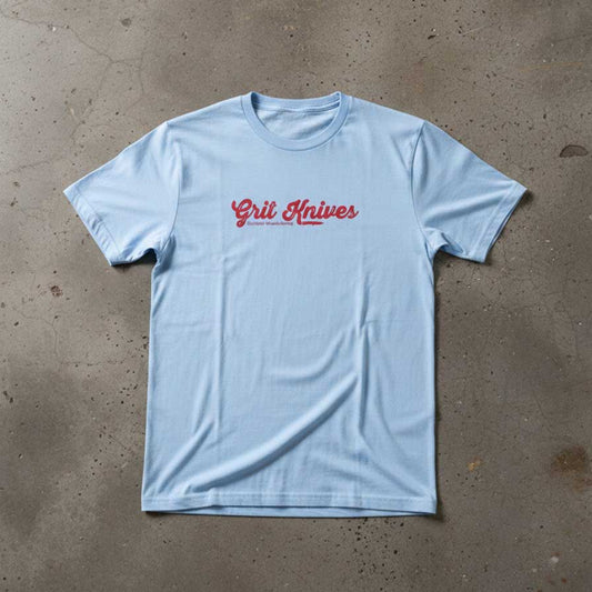 Light blue t-shirt with red text on a concrete floor